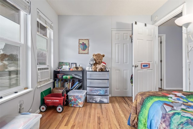 bedroom featuring cooling unit, wood finished floors, and a textured ceiling