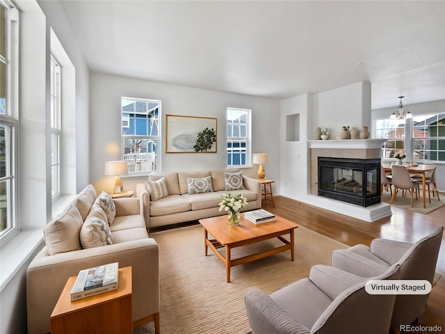 living room featuring an inviting chandelier, a fireplace, and light hardwood / wood-style floors