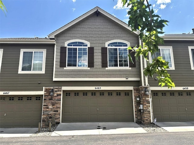 view of front of home featuring stone siding, an attached garage, and concrete driveway