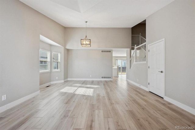 unfurnished room with plenty of natural light, light wood-style flooring, stairs, and visible vents