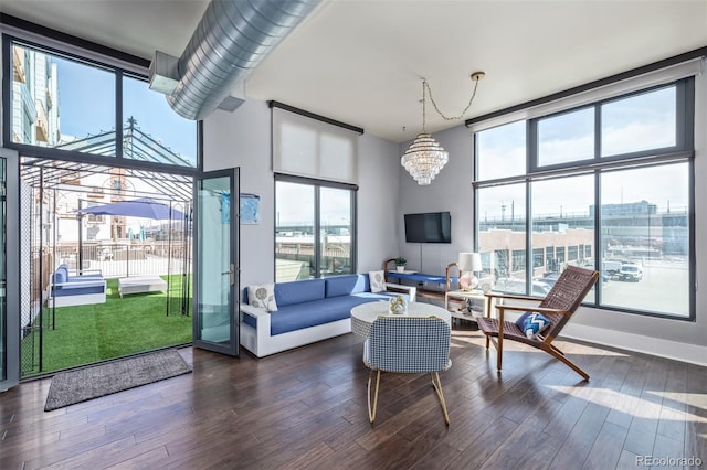 living room featuring expansive windows, dark wood-style flooring, a notable chandelier, and a healthy amount of sunlight
