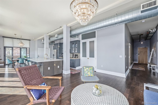 living area with visible vents, dark wood finished floors, baseboards, and a notable chandelier