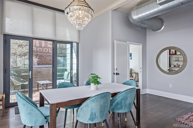 dining room featuring an inviting chandelier, baseboards, wood finished floors, and a towering ceiling