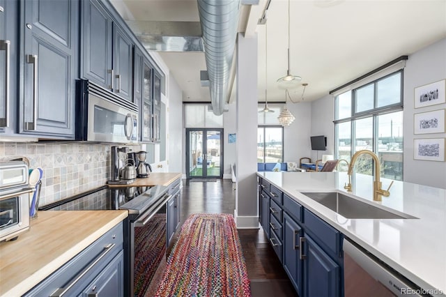 kitchen with a sink, appliances with stainless steel finishes, blue cabinets, and light countertops