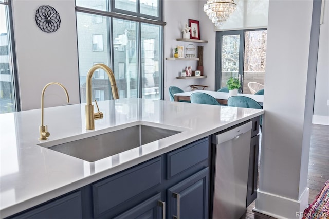 kitchen with stainless steel dishwasher, light countertops, a chandelier, a sink, and blue cabinetry