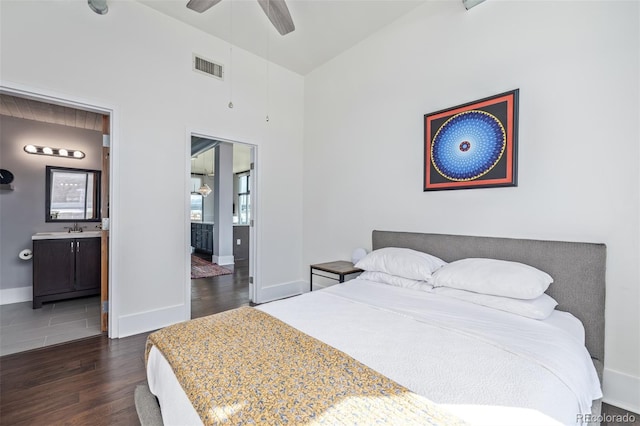 bedroom with visible vents, wood finished floors, a sink, baseboards, and ensuite bath