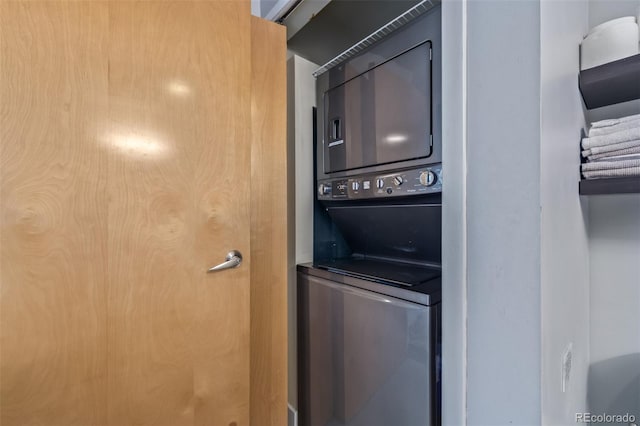 clothes washing area featuring stacked washing maching and dryer and laundry area