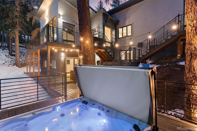 exterior space featuring a covered hot tub, a balcony, and stairs