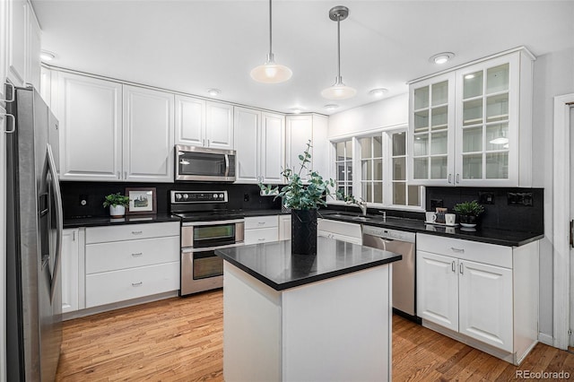 kitchen with sink, hanging light fixtures, stainless steel appliances, a center island, and white cabinets