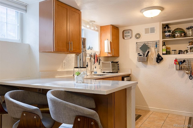 kitchen featuring a breakfast bar, kitchen peninsula, sink, and light tile patterned floors