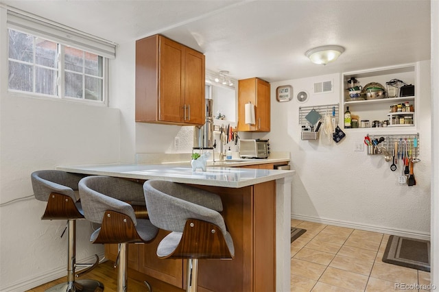 kitchen featuring kitchen peninsula, sink, a breakfast bar area, and light tile patterned floors