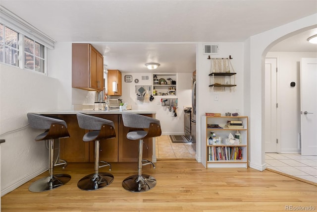 kitchen with light hardwood / wood-style flooring, a kitchen breakfast bar, and kitchen peninsula