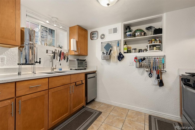 kitchen featuring sink, light tile patterned floors, range with gas cooktop, and dishwasher