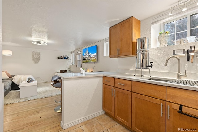 kitchen with sink, kitchen peninsula, and light wood-type flooring