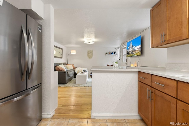 kitchen with stainless steel fridge, kitchen peninsula, and light tile patterned floors