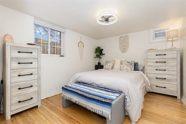 bedroom with a wall unit AC and light wood-type flooring