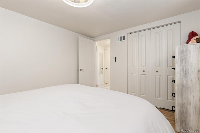 bedroom with light hardwood / wood-style floors and a closet