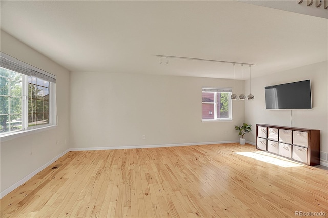 unfurnished living room with light wood-style flooring, baseboards, and track lighting