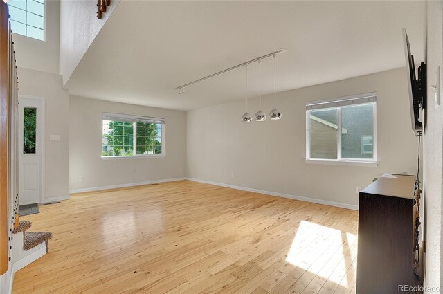 spare room with baseboards, rail lighting, and light wood finished floors