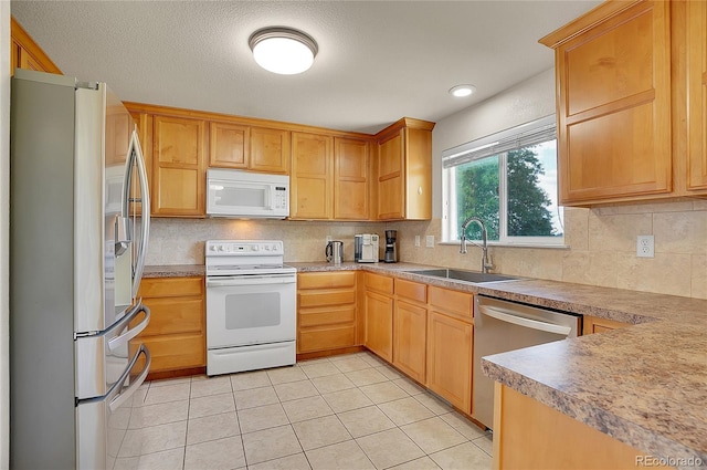 kitchen with light tile patterned floors, a sink, stainless steel appliances, a textured ceiling, and backsplash