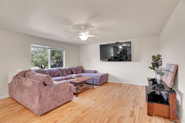 living room featuring ceiling fan, a textured ceiling, baseboards, and wood finished floors