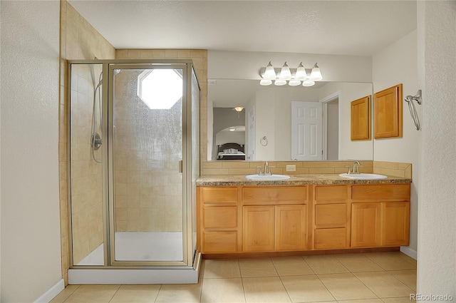 bathroom with double vanity, a stall shower, a sink, and tile patterned floors