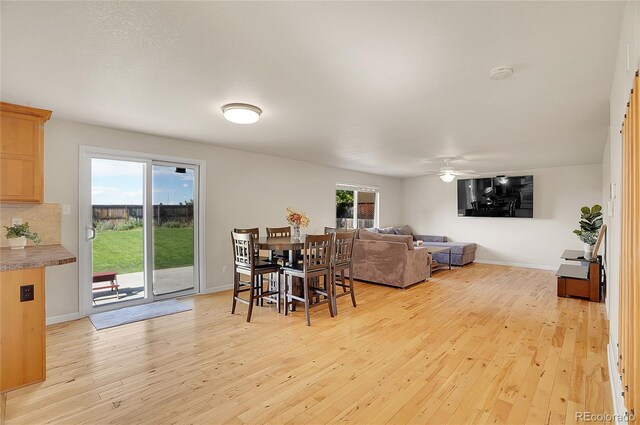 dining area with light wood-style floors, a healthy amount of sunlight, ceiling fan, and baseboards