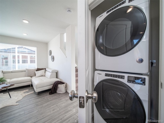 washroom with light wood-type flooring and stacked washer and clothes dryer