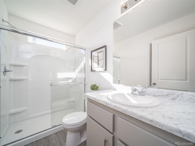 bathroom featuring hardwood / wood-style floors, vanity, toilet, and an enclosed shower