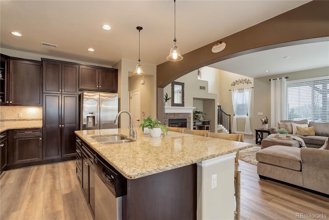 9592 Firenze Way, Highlands Ranch, CO 80126 - kitchen with stainless steel appliances, a sink, open floor plan, light wood-style floors, and dark brown cabinets