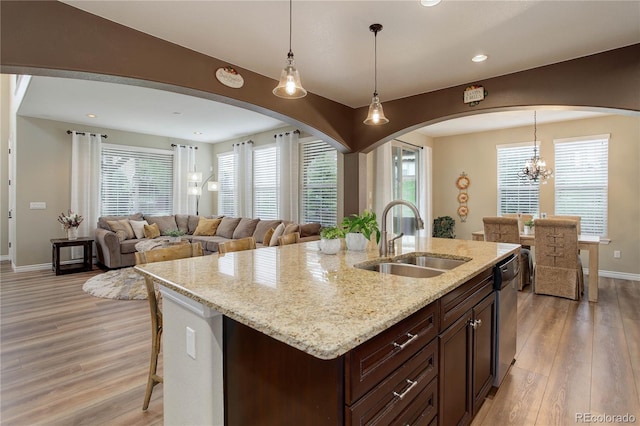 9592 Firenze Way, Highlands Ranch, CO 80126 - kitchen featuring a sink, arched walkways, baseboards, light wood-style flooring, and dishwasher