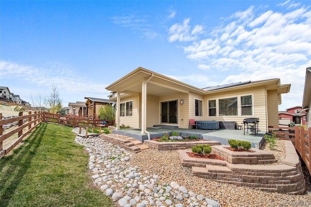 17670 W 94th Dr, Arvada, CO 80007 - back of house with roof mounted solar panels, a fenced backyard, a lawn, and a patio area