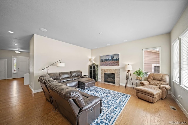 17670 W 94th Dr, Arvada, CO 80007 - living room featuring baseboards, a wealth of natural light, wood finished floors, and a tiled fireplace