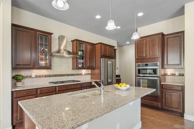 17670 W 94th Dr, Arvada, CO 80007 - kitchen with appliances with stainless steel finishes, hanging light fixtures, tasteful backsplash, a sink, and wall chimney exhaust hood
