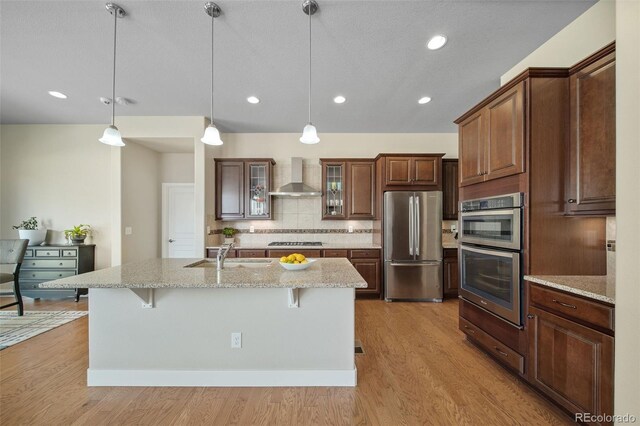 17670 W 94th Dr, Arvada, CO 80007 - kitchen with decorative backsplash, a kitchen bar, wall chimney exhaust hood, a sink, and appliances with stainless steel finishes