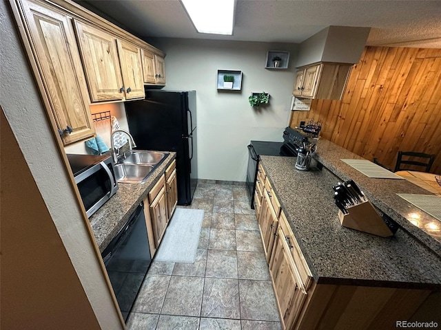 kitchen with sink, light brown cabinets, black appliances, and wood walls