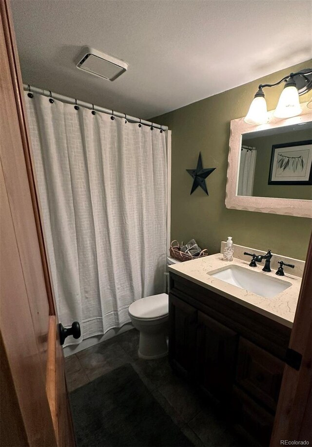 bathroom with vanity, toilet, tile patterned flooring, and a textured ceiling