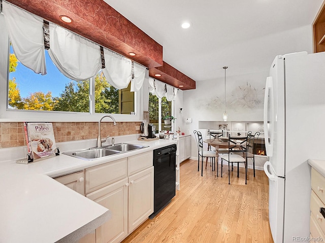 kitchen with black dishwasher, light wood-type flooring, sink, white fridge, and decorative light fixtures