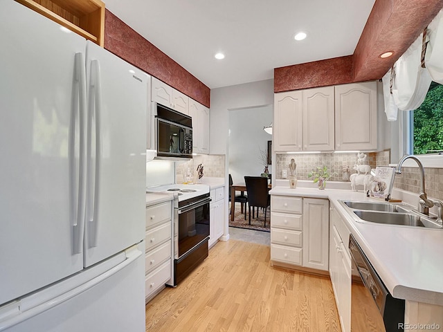 kitchen featuring black appliances, sink, backsplash, white cabinets, and light hardwood / wood-style flooring