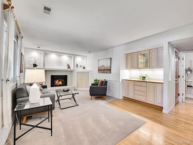 living room featuring light hardwood / wood-style flooring and a brick fireplace