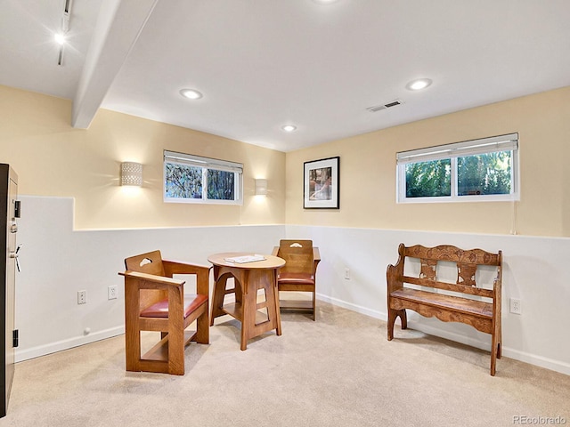 dining area with light carpet and beamed ceiling