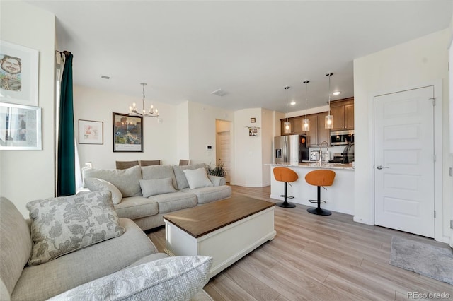 living room featuring a chandelier and light hardwood / wood-style flooring