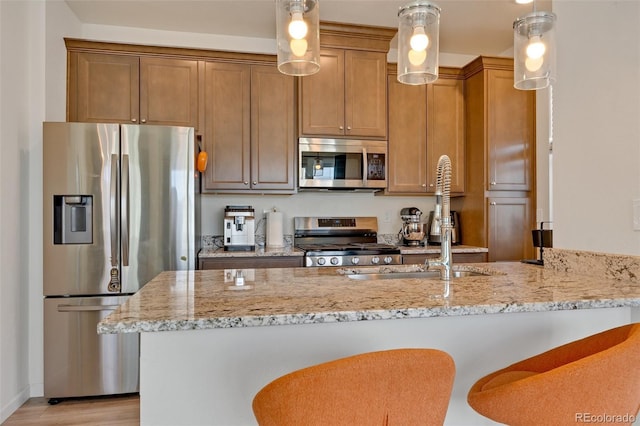 kitchen featuring sink, light stone countertops, appliances with stainless steel finishes, light hardwood / wood-style floors, and kitchen peninsula