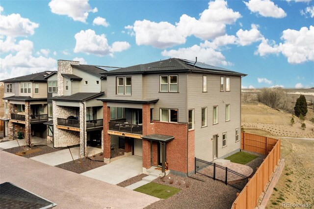 15606 W Girard Ave, Morrison, CO 80465 - rear view of property featuring concrete driveway, a fenced backyard, a balcony, solar panels, and a garage