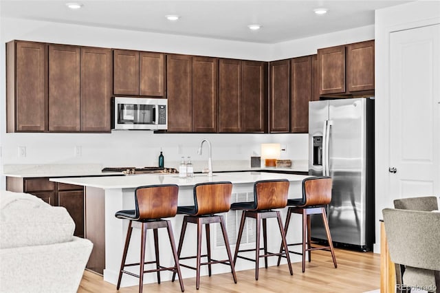 15606 W Girard Ave, Morrison, CO 80465 - kitchen featuring a center island with sink, light wood-type flooring, dark brown cabinetry, and stainless steel appliances