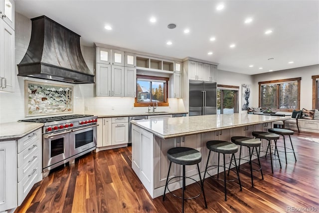 kitchen with premium range hood, a kitchen island, white cabinetry, and premium appliances