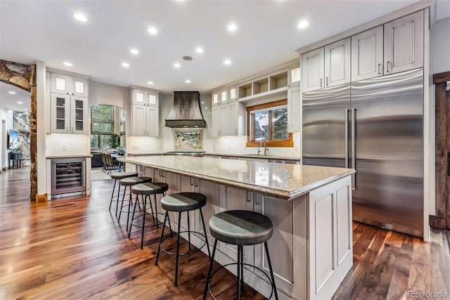 kitchen featuring a spacious island, beverage cooler, appliances with stainless steel finishes, custom exhaust hood, and plenty of natural light