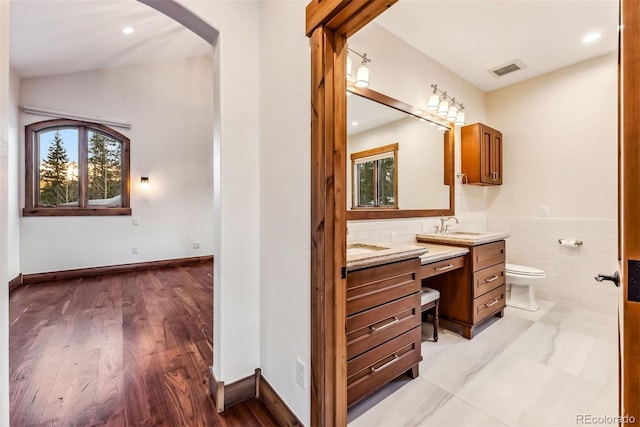 bathroom with toilet, vanity, and tile walls