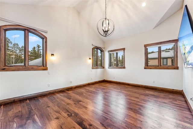 spare room featuring an inviting chandelier, dark hardwood / wood-style flooring, and lofted ceiling