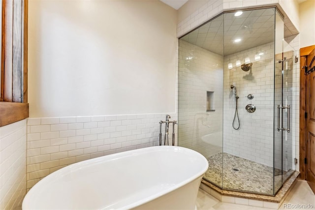 bathroom with tile walls and independent shower and bath